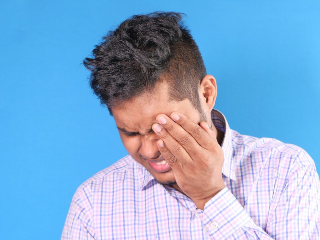 a man frowning and rubbing his temple as if he has a headache