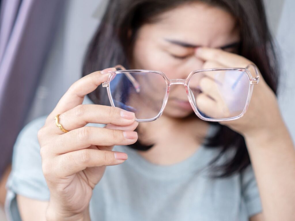 a woman who has taken off her eyeglasses and is rubbing the bridge of her nose as if she has a headache