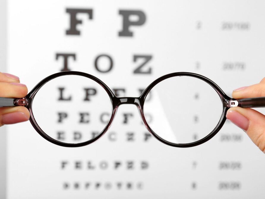 eyeglasses in front of an optometrist chart with letters