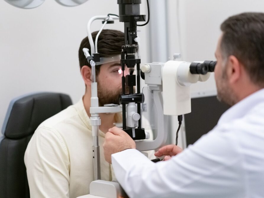 optometrist giving an eye exam to a male patient