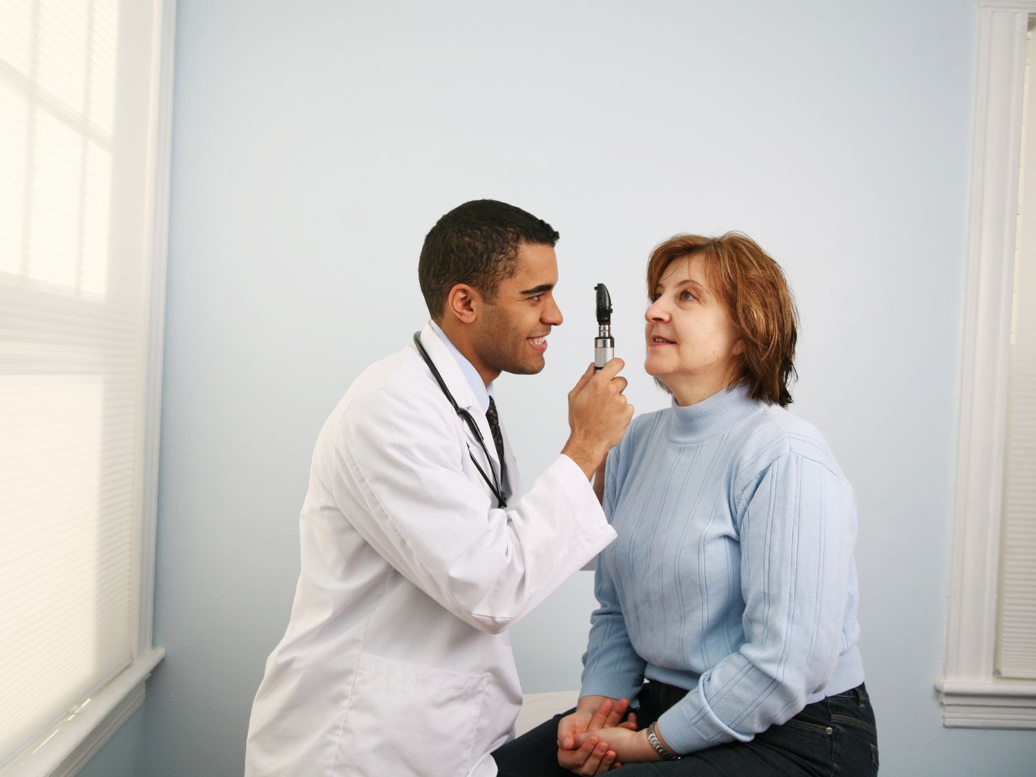 optometrist looking into the eye of a female patient